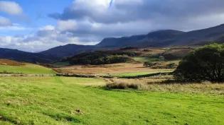 A grassy field with hills in the background with Pululahua Geobotanical Reserve in the background