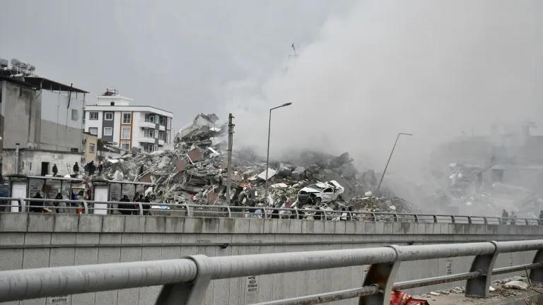 Collapsed buildings and smoke show the aftermath of an earthquake