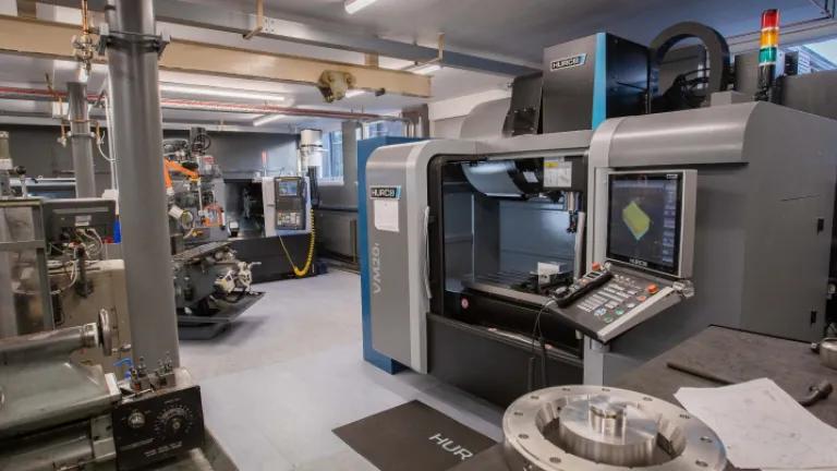 Interior photograph of GeoSciences mechanical workshop showing machinery including a tooling lathe