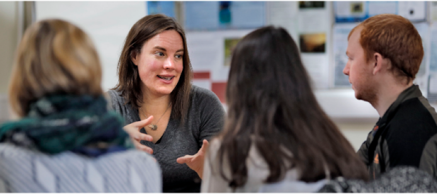 A group of University research students in a classroom talking and laughing
