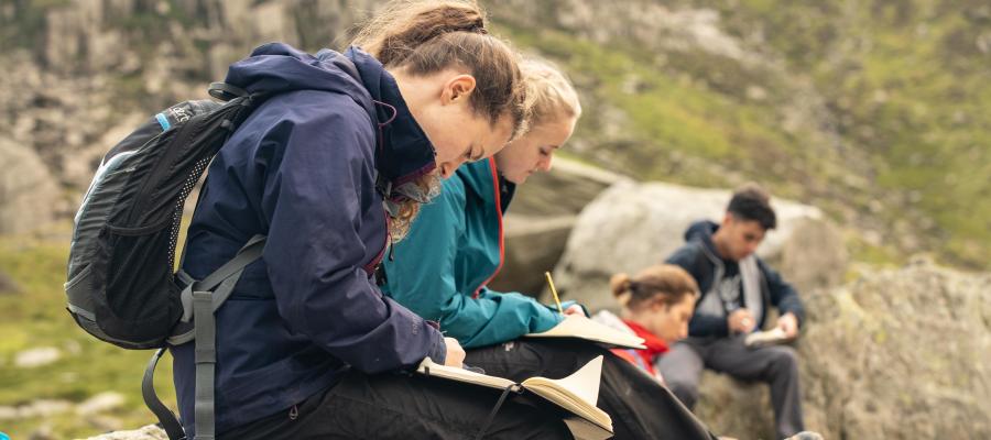 Group of students on Snowdonia field trip writing in their notebooks