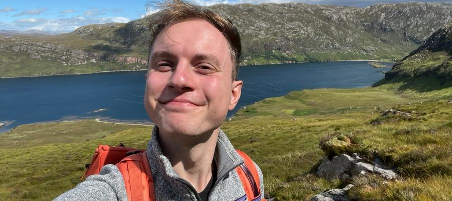 Vojta posing for a photo in front of a lake and mountain