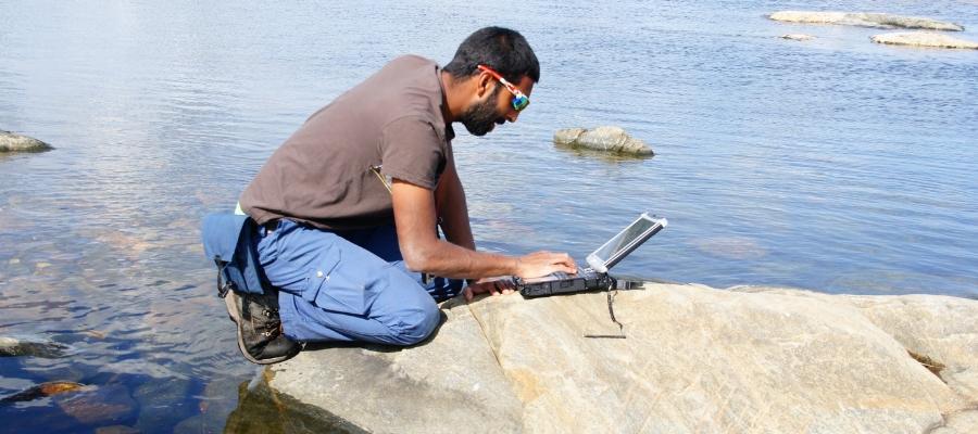 Romesh conducting survey work on his laptop.