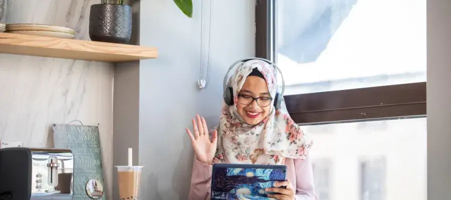 Woman taking a video call and waving at the screen