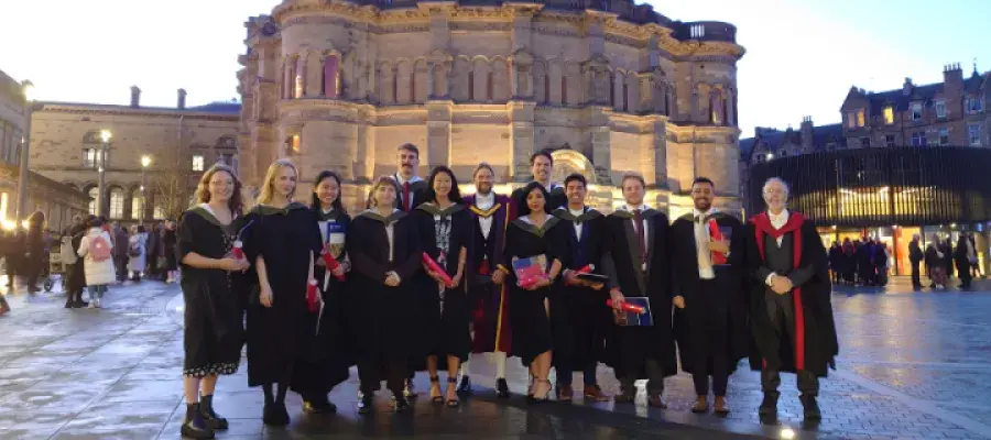 Photo shows graduates in gowns stood outside McEwan Hall with programme staffh