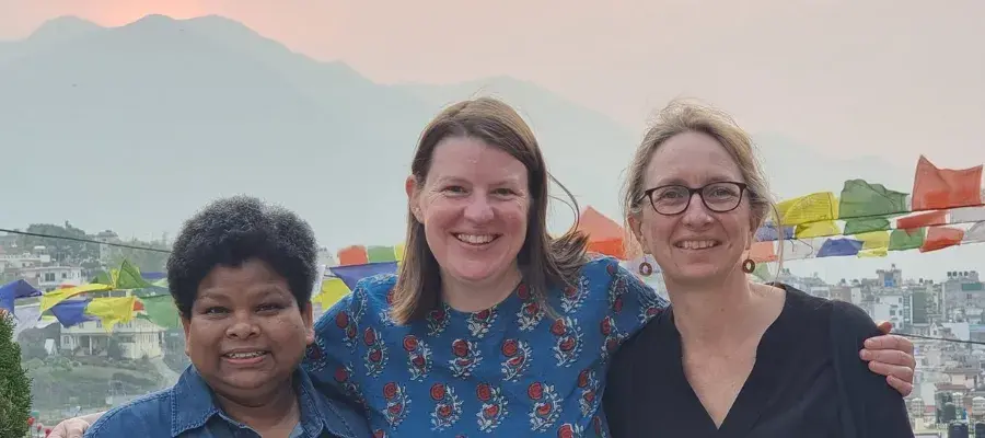 Reggie, Clare and Sam posing for a photo while in Nepal, with a mountain in the background.