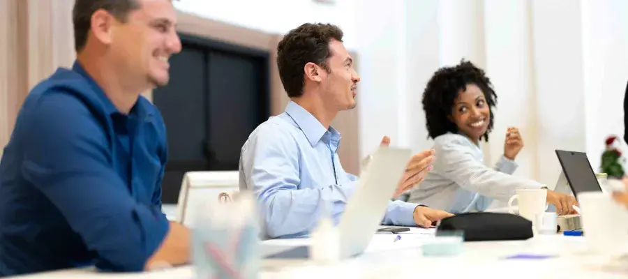 People sitting at a desk with laptops and stationery during a meeting talking