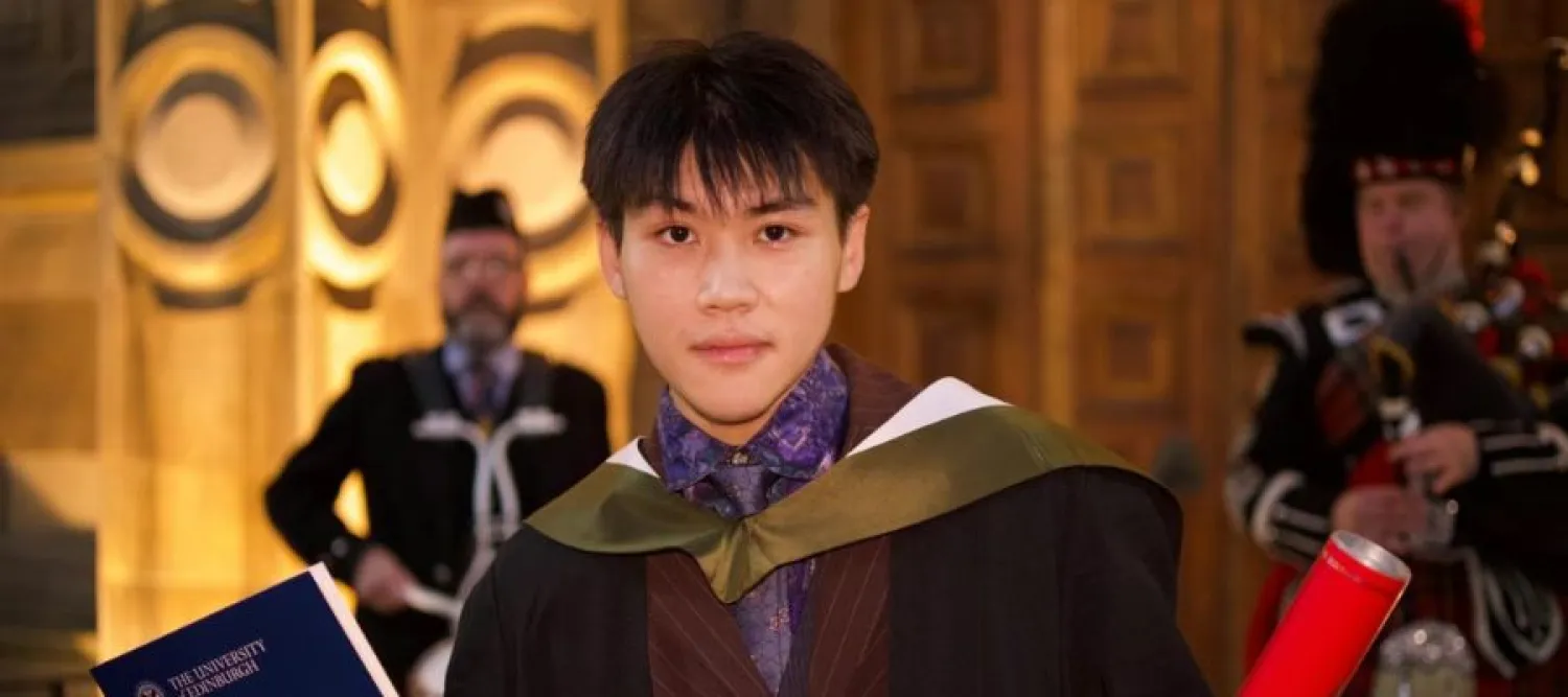 Rongsheng poses for a photo in his graduation gown, holding his degree certificate and scroll.