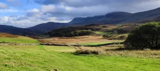 A grassy field with hills in the background with Pululahua Geobotanical Reserve in the background