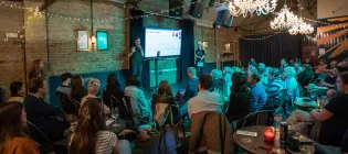 A speaker delivering a presentation a crowded pub.