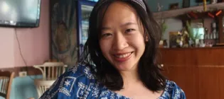 Siying smiling for a photo while sitting in a cafe.