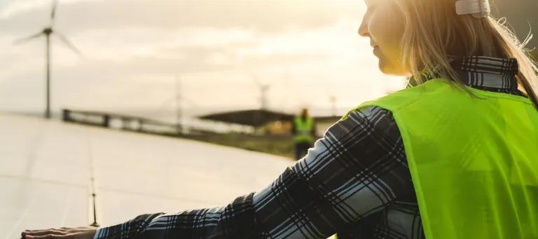 A woman in protective clothing stood in front of a solar panel