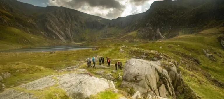 A group of people are seen in the distance walking through the rocky landscape of Snowdonia
