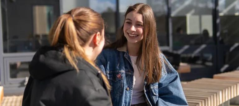 Two students sitting together chatting outside