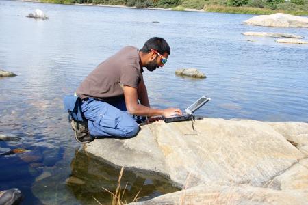 Romesh conducting survey work on his laptop.