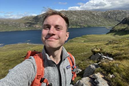 Vojta posing for a photo in front of a lake and mountain