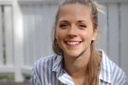 Emma smiling at the camera wearing a blue and white striped shirt.