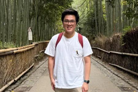 Gary smiles for the camera while standing on a path surrounded by trees.