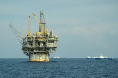 An oil rig in the sea with a tanker ship in the background