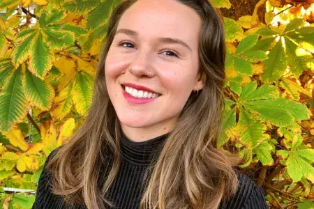 Photo shows Alexa stood in front of an autumnal tree