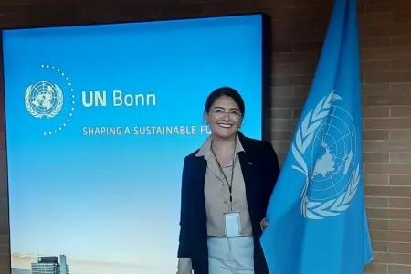 Valentina DaCosta standing beside a UN flag at a UN conference.