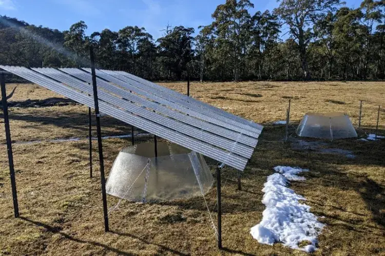 A rainout shelter with a warming chamber below it is placed in the middle of a field