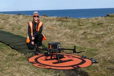 Amy posing for a photo next to a drone