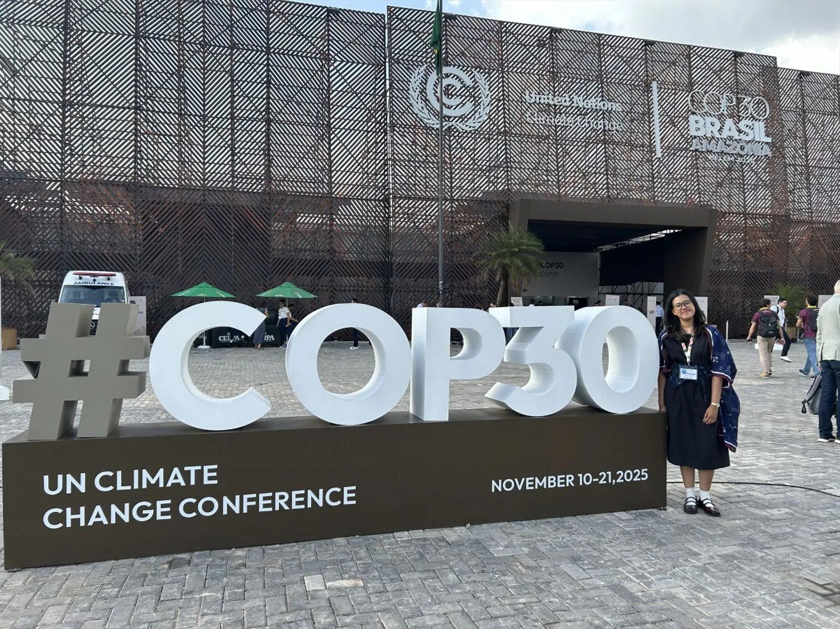 Via standing next to a COP30 sign.