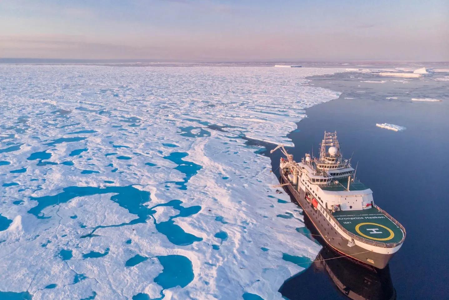 Aerial view of research ship next to very large section of sea ice