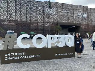 Via standing next to a COP30 sign.