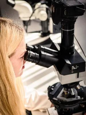 A woman looking into a microscope lens