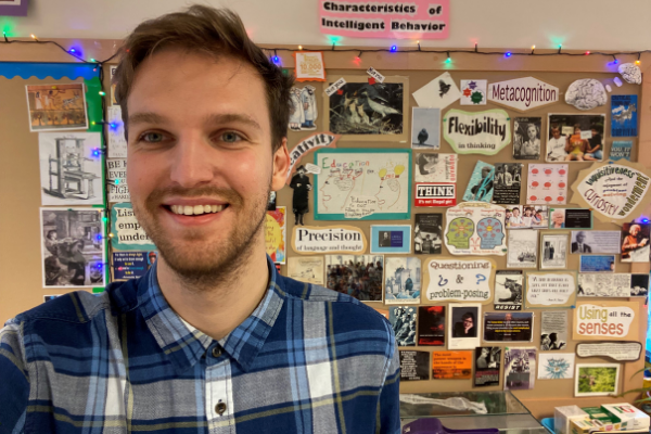 photo shows Rob standing in front of a vision board