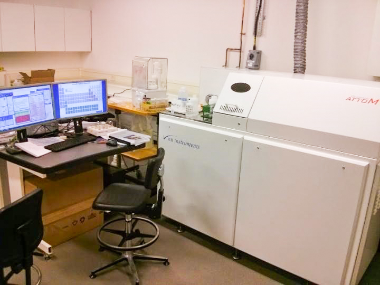 Inside a laboratory with a computer, desk and chair next to scientific equipment