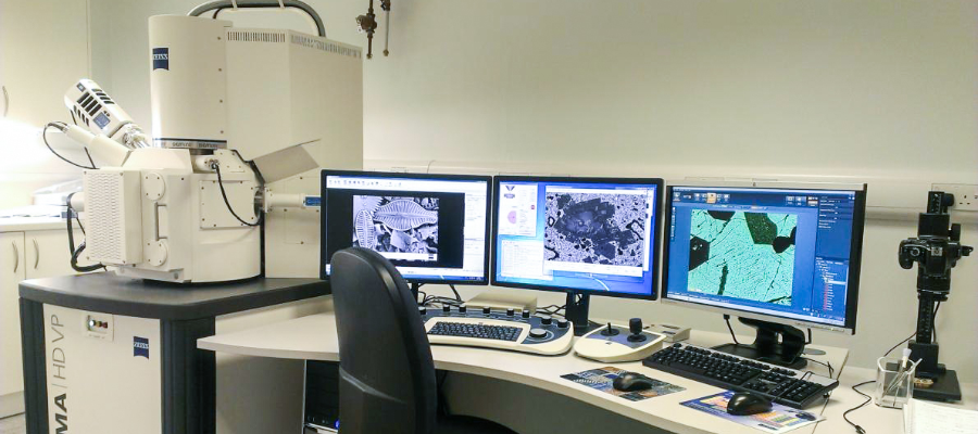 A chair and desk with 3 computer screens next to scientific equipment in the laboratory