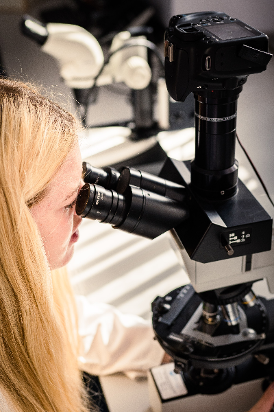 A woman looking into a microscope lens