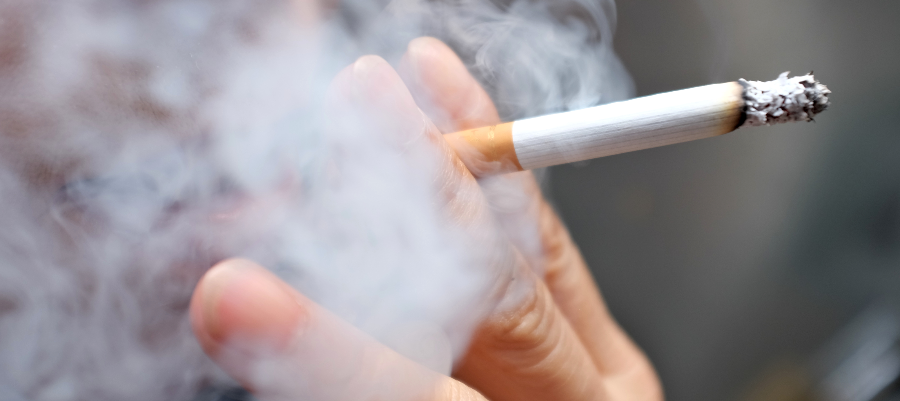 A close up of a man's hands holding a smoking cigarette