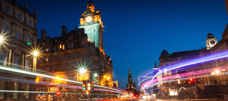 Intersection of an Edinburgh city street at night, with streaks of light from the passing traffic