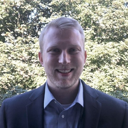 Cameron in a suit, smiling in his garden.