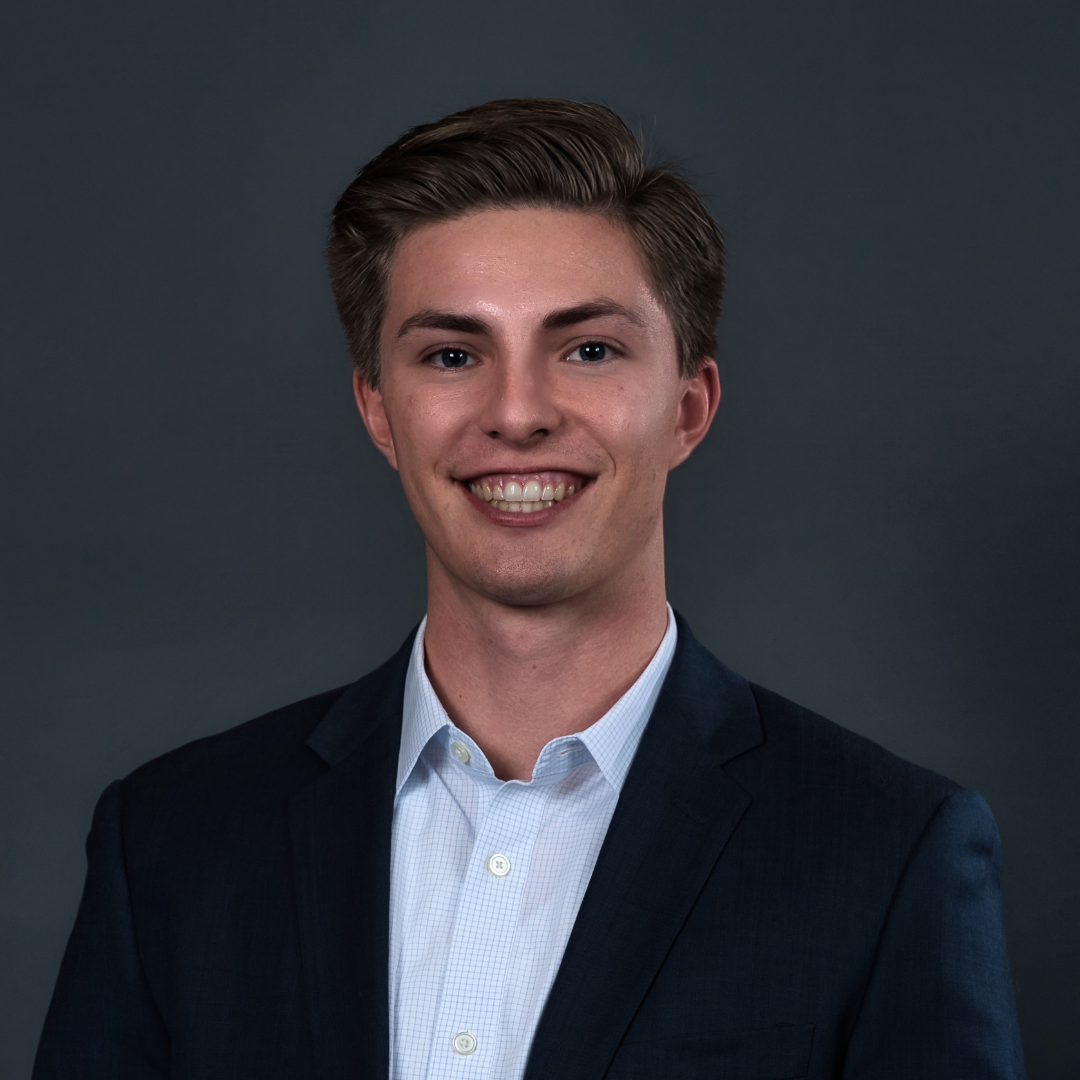 Man standing in front of a dark background and smiling at the camera 