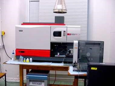 Inside a laboratory with a computer, desk and chair next to scientific equipment