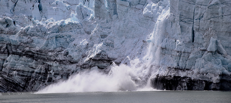 A large section of melting ice falling off a glacier into the sea