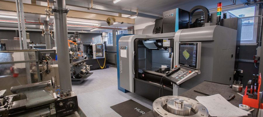 Interior photograph of GeoSciences mechanical workshop showing machinery including a tooling lathe