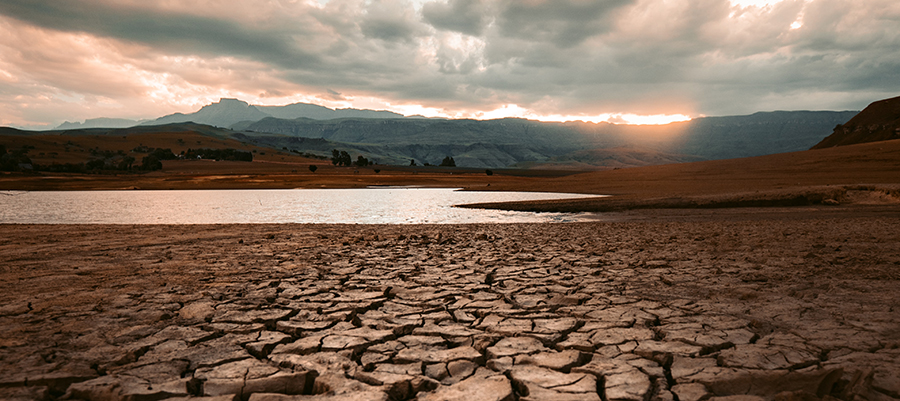 A lake and mountain are pictured, with the lake foreground dried up and cracked due to drought